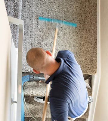 MSS Cleaning employee using a carpet rake to groom carpet, eliminating lines and depressions in freshly cleaned carpet