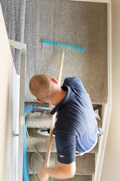 MSS Cleaning employee using a carpet rake to groom carpet