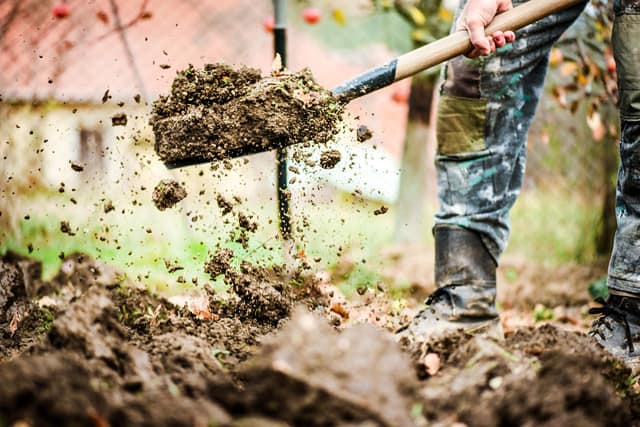 shoveling dirt away from foundation to keep water from flooding basement