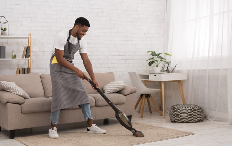 Man vacuuming rug in home